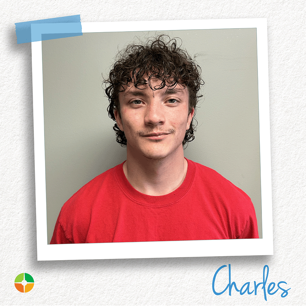 A young man with curly hair wears a red shirt and looks directly at the camera against a neutral background. His relaxed expression and casual style create a simple, confident portrait that highlights his personality and approachable demeanor. A young man with curly hair wears a red shirt and looks directly at the camera against a neutral background. His relaxed expression and casual style create a simple, confident portrait that highlights his personality and approachable demeanor.