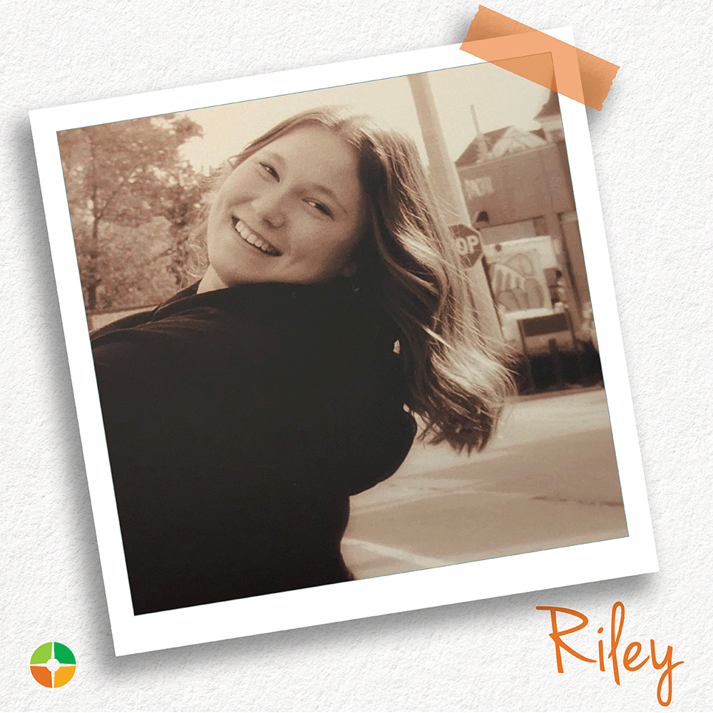 Polaroid-style photo of a smiling young woman with long hair turning toward the camera outdoors. The image has a warm, vintage tone. A small logo appears in the corner, and the name “Riley” is written in orange text at the bottom right.